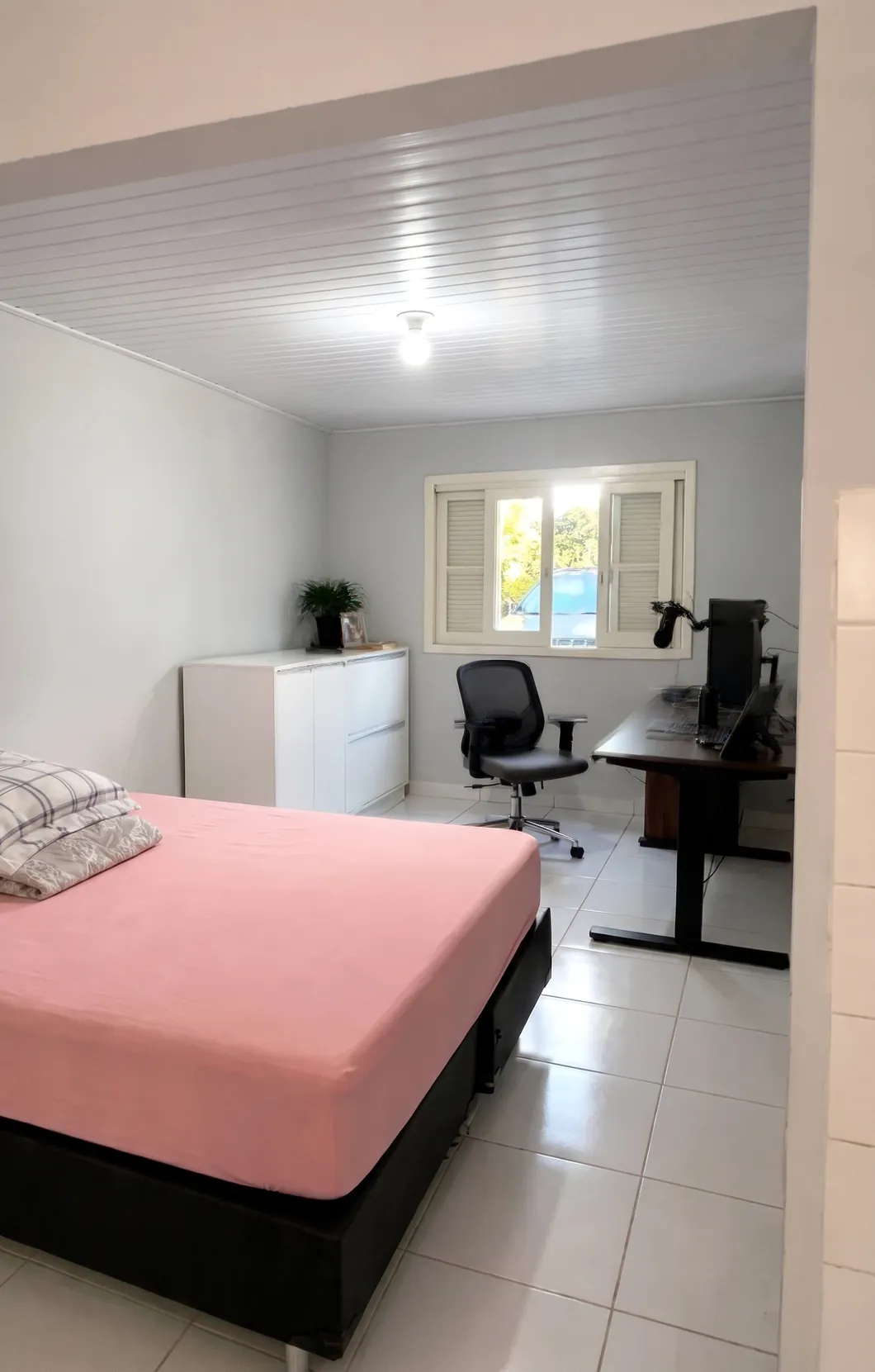 Terceiro dormitório usado como quarto e escritório, com escrivaninha, cadeira e janela para o quintal.